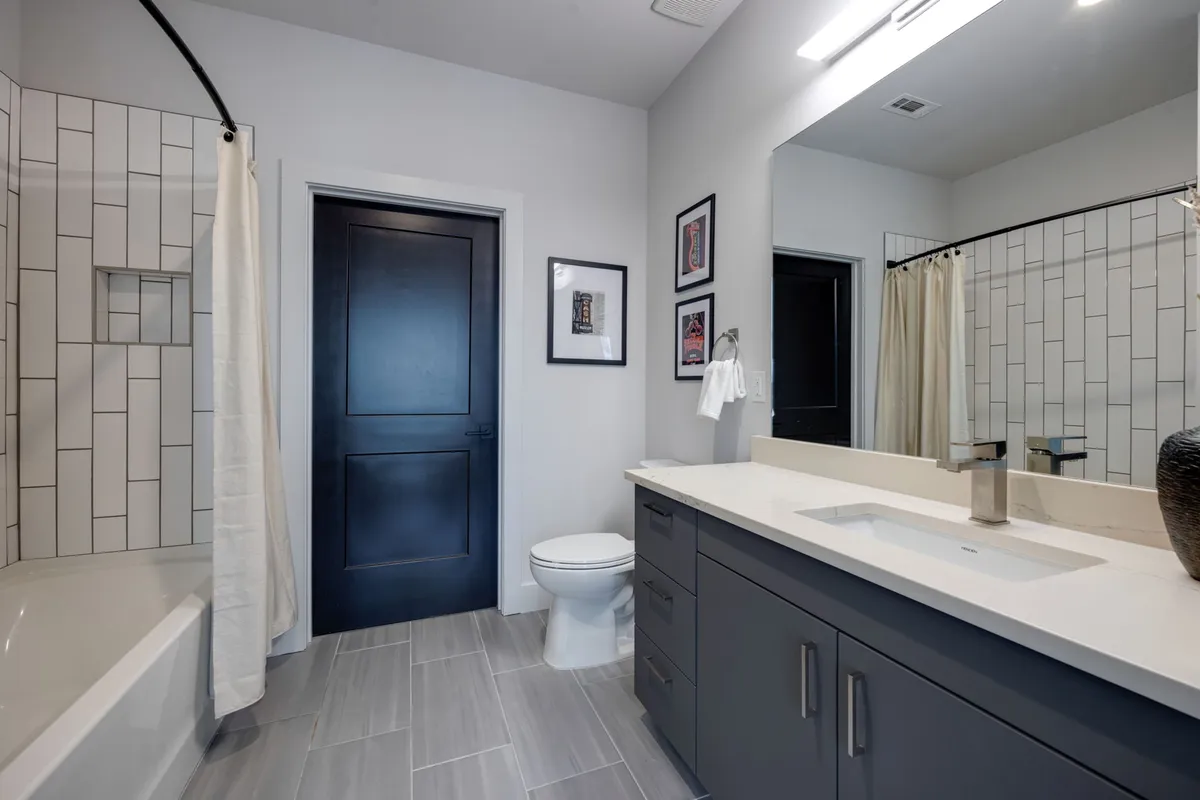 A serene, spa-style bathroom with a vanity and sink, framed artwork, a bathtub, and a toilet. The space is organized, clean, and designed for rejuvenating routines.