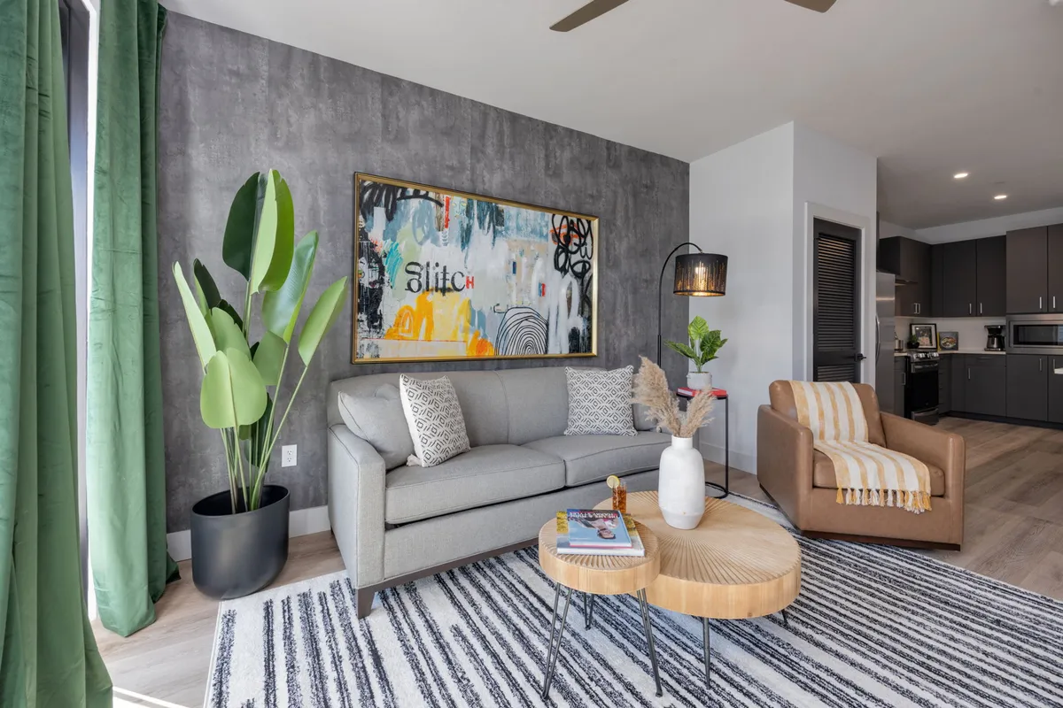 A modern, cozy living area featuring a soft sofa, coffee table, a decorative plant, and abstract artwork. The setting is perfect for relaxing or hosting guests, tying in the home’s flexibility for additional sleeping arrangements via the sleeper sofa.
