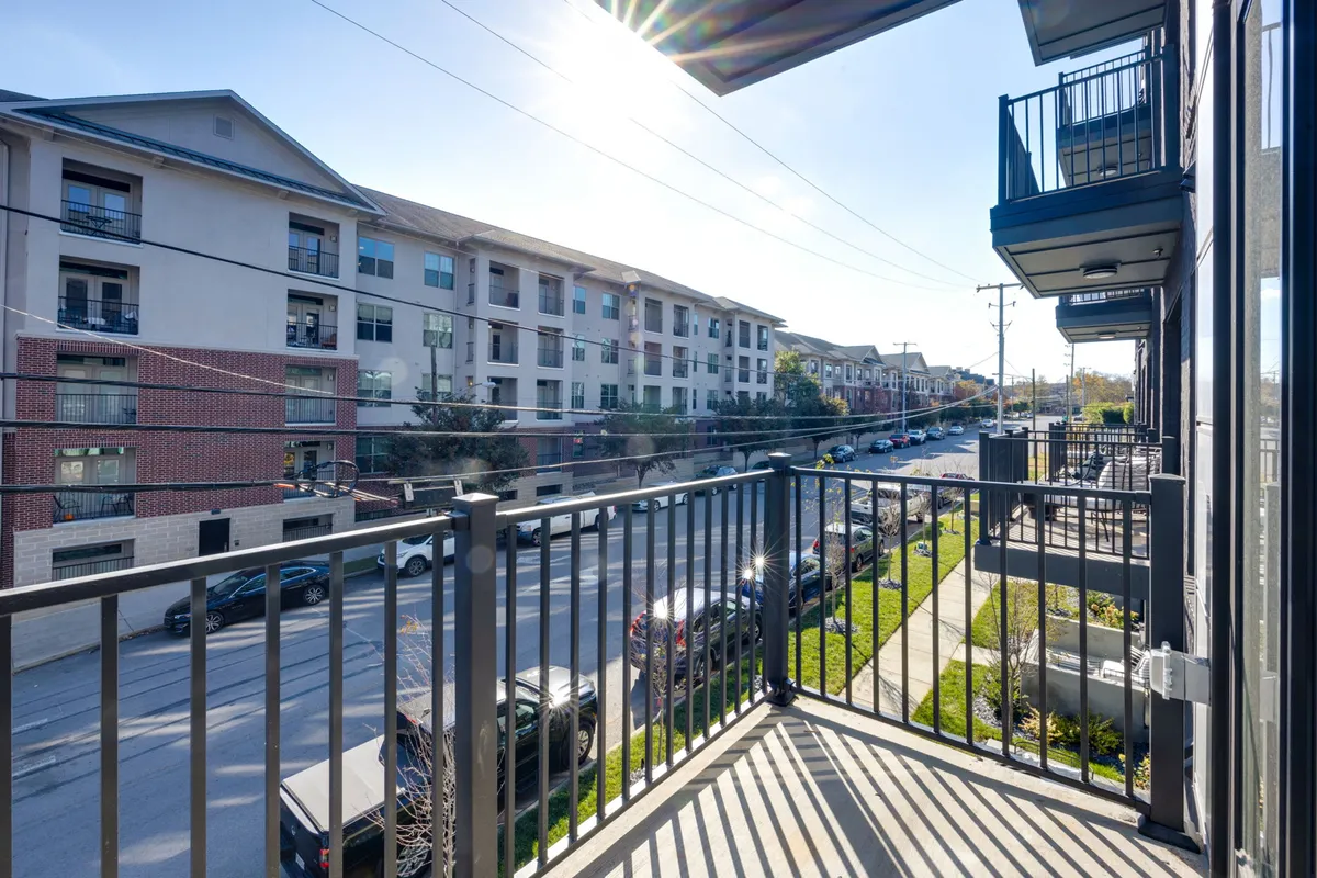 A welcoming exterior shot from a private balcony overlooking Midtown's bustling streets and surrounding buildings, bathed in natural sunlight. The view suggests a relaxing spot to unwind while staying connected to the city's vibrant atmosphere.